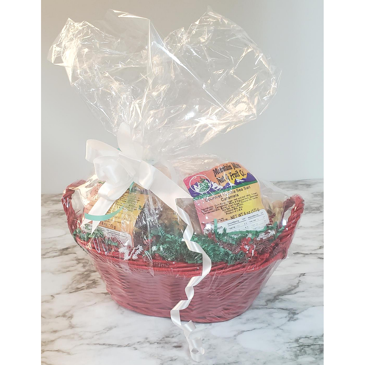 Example of our Small Build Your Own Custom Gift Basket - Red basket wrapped in clear cello with a white ribbon.